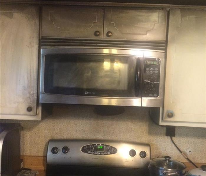 Kitchen stove and cabinets covered in soot from a fire 