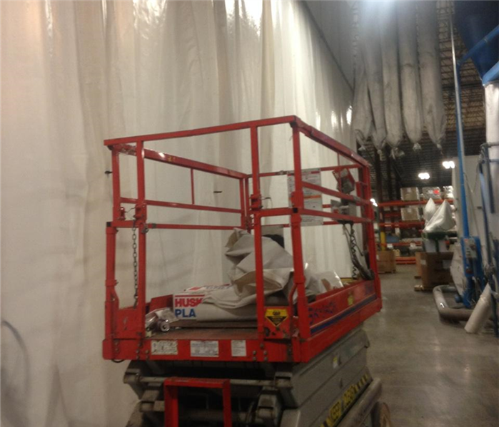 A SERVPRO employee in a boom lift cleaning a high ceiling in a Scranton plastics manufacturer