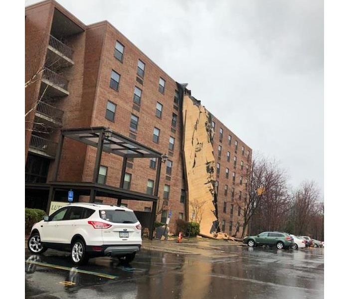 A big building with the roof hanging over the side from a wind storm.