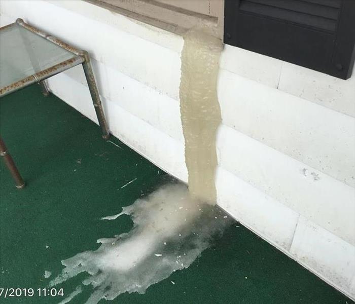 Frozen water emerging from a picture window in a home in Hamlin